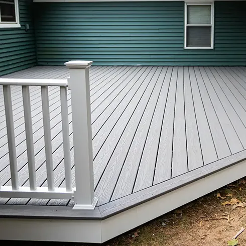 Detailed view of a modern, well-constructed deck with a white railing, showcasing high-quality materials and design for enhanced outdoor living spaces.