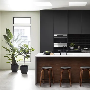 Stylish modern kitchen featuring sleek cabinetry, a plant on the counter, and contemporary bar stools.