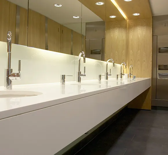 Spacious commercial bathroom featuring white sinks, sleek countertops, and modern lighting.