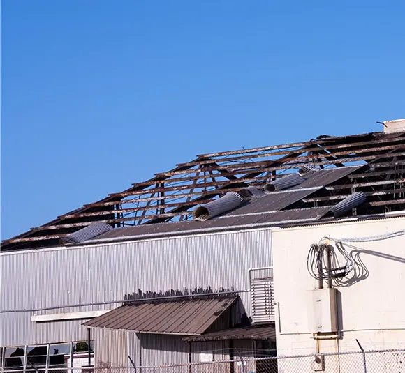 View of a commercial building's roof showing significant storm damage, illustrating the need for professional storm damage repair in Richmond, VA.