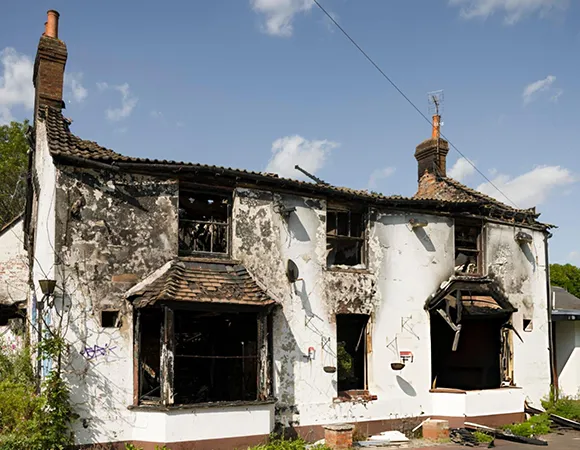 Exterior view of a heavily damaged house after a fire, highlighting the extensive repair work required following fire incidents.