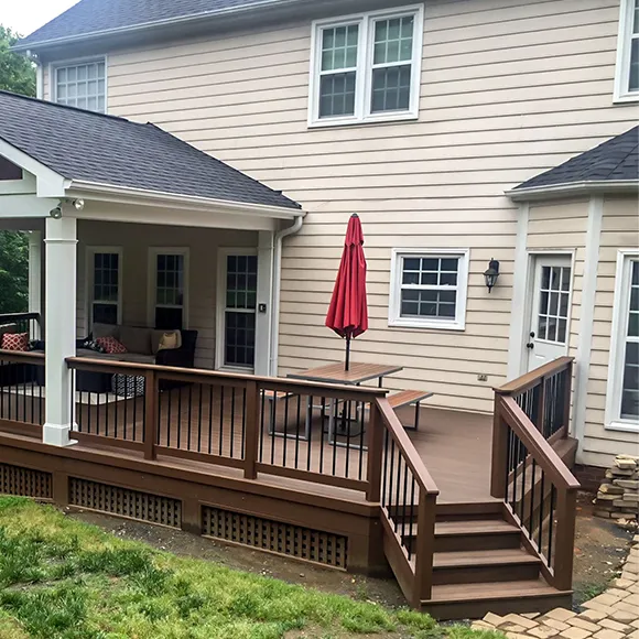 Exterior view of a well-maintained deck attached to a house, featuring seating and an umbrella, showcasing deck repair and enhancement services.
