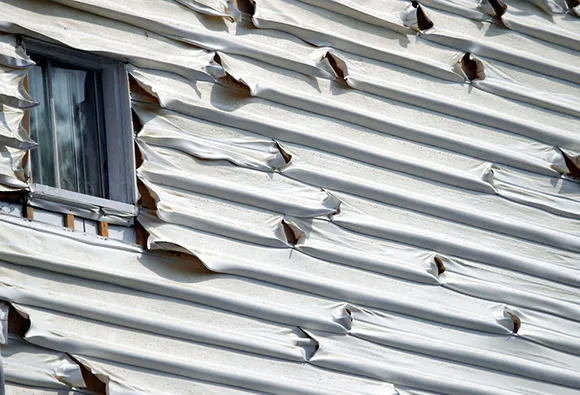 Close-up of repaired siding showing remnants of hail damage and a textured surface.