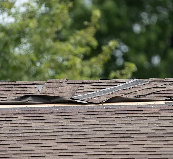 Detailed view of a roof showing signs of damage from a recent storm, emphasizing the expertise of storm damage roofing contractors in Mechanicville, VA.