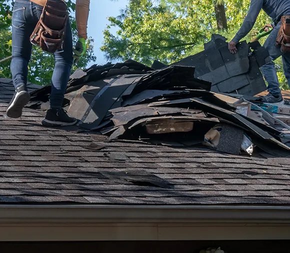 Roofers repairing a residential roof with visible storm damage, highlighting residential storm damage repair services in Henrico, VA.