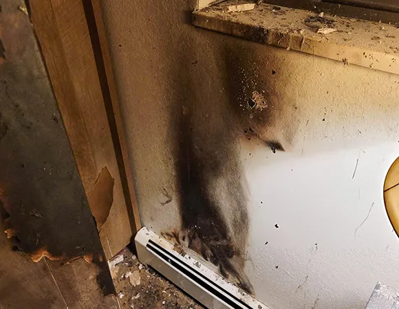 Close-up of blackened walls and soot residue in a home following a fire, illustrating the extent of smoke damage and the need for specialized cleanup.
