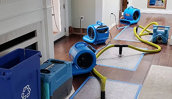 Close-up of blue water restoration fans and equipment set up for drying, illustrating professional water mitigation solutions in a damaged area.
